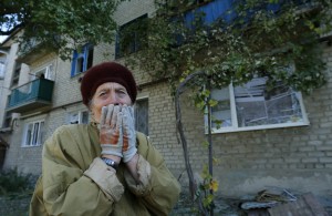Maria Savchenko, 60, reacts as she sits in front of her home which was damaged by shelling a day before in the village of Pisky, near Donetsk in eastern Ukraine